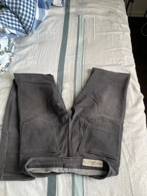 Gråa raka jeans med stora fickor - Säljer ett par gråa jeans med raka ben och stora fickor framtill. Jeansen har klassisk femficksdesign och är tillverkade i ett mjukt denimtyg. Perfekta för dig som gillar en enkel och clean stil.