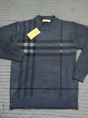 Burberry tröja  - Snygg grå stickad tröja från Burberry med klassiskt rutmönster i svart, vitt och vinrött. Tröjan har rund halsringning, ribbade muddar och en stilren design som passar perfekt till jeans eller chinos.