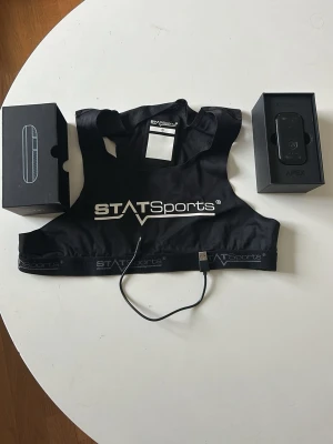 STATSports gps tracker för fotboll  - Pulsmätarväst från STATSports i svart med vit logga, storlek S. Västen är tillverkad i ett stretchigt och ventilerande material och kommer med tillhörande sensor och laddkabel. Perfekt för dig som vill mäta puls och aktivitet under träning. Knappt använd men rekommenderar starkt för fotbollspelare nypris 3000 ish 