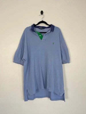 Polo Ralph Lauren Pikétröja XL Ljusblå Grön Logo 100% Bomull Classic Fit Herr Vintage - • Storlek: XL • Färg: Ljusblå med mörkblå krage, grön knappslå och grön broderad Pony-logotyp • Passform: Classic Fit • Krage: Klassisk ribbstickad pikékrage med tvåknappsstolpe • Material: 100% bomull   Skick: Plagget är i väldigt fint skick med få väldigt små fläckar på bakaxeln. Eventuella anmärkningar anges alltid tydligt i beskrivningen och visas på bilderna.  Nypris: Cirka 1 500 kr.  📦 Skickas snabbt och packas omsorgsfullt. 💬 Hör gärna av dig om du har frågor eller vill se fler bilder. 🤝 