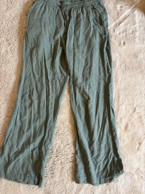 Gröna linnebyxor - Snygga gröna linnebyxor med avslappnad passform och resår i midjan. Byxorna har snedställda fickor och raka ben, perfekta för en chill och trendig look. Tillverkade i lätt och luftigt linnematerial.