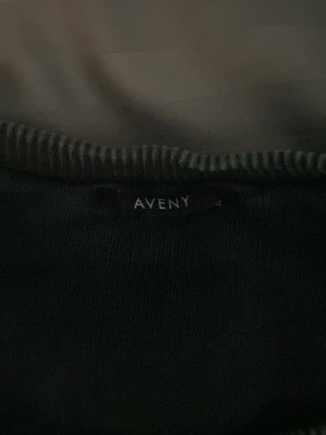 Grå sweatshirt från AVENY - En stilren grå sweatshirt från AVENY med rund halsringning och ribbade muddar vid ärmslut och nederkant. Tröjan har en avslappnad passform och är tillverkad i mjukt material, perfekt för en casual look.