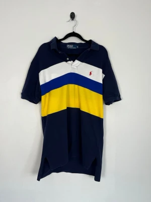 Polo Ralph Lauren Pikétröja M Marinblå Flerfärgad Rugby Pike 100% Bomull Klassisk Fit - • Storlek: M • Färg: Marinblå, vit, klarblå och gul med röd broderad Pony-logotyp • Passform: Classic Fit  • Krage: Klassisk ribbstickad pikékrage med tvåknappsstolpe • Material: 100% bomull  Skick: Plagget är i väldigt fint skick. Eventuella anmärkningar anges alltid tydligt i  beskrivningen och visas på bilderna.  Nypris: Cirka 1 600 kr.  📦 Skickas snabbt och packas omsorgsfullt. 💬 Hör gärna av dig om du har frågor eller vill se fler bilder. 🤝 Samfrakt erbjuds vid köp av flera plagg – kika gär