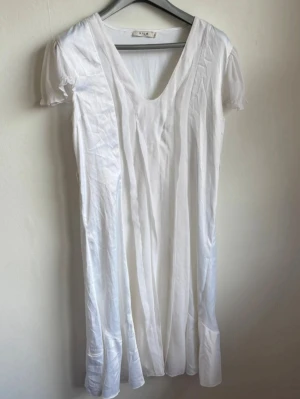 Vit midiklänning Vila "Jill Dress" - Säljer en jättefin, vit midiklänning från Vila i storlek L (modell Jill Dress X-B). Klänningen har korta, tunna chiffongärmar och en smickrande V-ringning. Framsidan har fina draperade paneler i olika texturer och baksidan har ett elastiskt band i midjan för en bekväm passform samt ett snyggt fall nedtill  Märke: Vila Clothes  Storlek: L  Färg: Vit  Material: Skal/Yttertyg: 100% Polyester | Foder: 100% Viskos  Skick: Bra begagnat skick  Djur- och rökfritt. Skickas snabbt! 