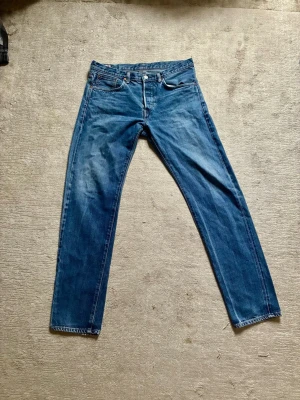 Edwin jeans  - Säljer ett par klassiska blå jeans med rak passform och fem fickor. Jeansen är tillverkade i Japan och har en snygg tvättad look med subtila slitningar. Materialet är kraftig denim som ger en autentisk känsla. Perfekta för dig som gillar stilrena och tidlösa jeans.