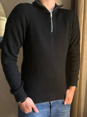 Svart ribbstickad tröja med halv dragkedja - Snygg svart ribbstickad tröja med halv dragkedja i halsen. Tröjan har lång ärm, hög krage och är tillverkad i ett mjukt stickat material. Perfekt för dig som gillar en stilren och enkel look.