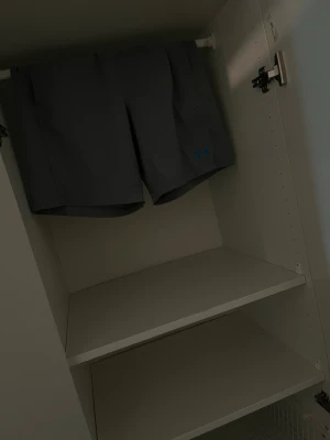Grå träningsshorts från Under Armour - Säljer ett par grå träningsshorts från Under Armour med snörning i midjan och logga på benet. Shortsen har en relaxed fit och är perfekta för gymmet eller löprundan. Tillverkade i ett lätt och snabbtorkande material.