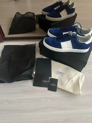 Blå och vita sneakers från Valentino 42 - Snygga sneakers från Valentino i blå mocka och vitt läder. Skorna har en klassisk låg siluett med vita sulor och blå snörning. Perfekta för dig som vill ha en stilren och trendig look. Kommer med originalpåse och box.