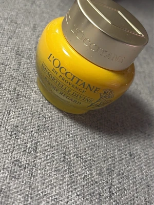 L'Occitane Immortelle Divine ögonbalsam - L'Occitane Immortelle Divine Baume Regard är ett lyxigt ögonbalsam i en gul glasburk med silverfärgat lock. Produkten har en krämig konsistens och är framtagen för att vårda huden runt ögonen. Perfekt för dig som vill boosta din hudvårdsrutin.