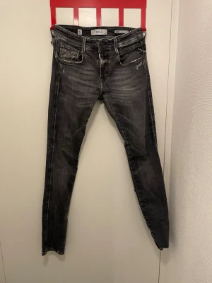 Svarta slim fit jeans från Replay - Snygga svarta slim fit jeans från Replay, modell Anbass. Jeansen har slitna detaljer. Perfekta för en trendig och avslappnad stil. Tillverkade i stretchigt denim för extra komfort. Säljes pga blivit för små för mig!