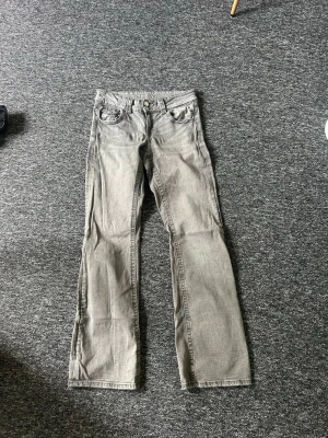 Grå raka jeans med dubbla knappar - Säljer ett par grå jeans med raka ben och dubbla knappar i midjan. Jeansens lapp är borta men är ganska säker på storleken, Materialet är denim och färgen är tvättad grå, vilket ger en cool och avslappnad vibe.