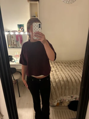 Vinröd kortärmad stickad tröja - Mysig vinröd stickad tröja med boxy passform och korta ärmar. Tröjan har rund halsringning och ribbade kanter. Perfekt att styla med både jeans och kjol för en avslappnad look.