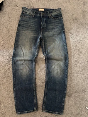 Blå jeans straight leg  - Säljer ett par blå jeans med snygga slitningar och tvättade detaljer på låren och knäna. Klassisk femficksmodell med raka ben och normal midja. Perfekt för dig som gillar en avslappnad och cool stil.