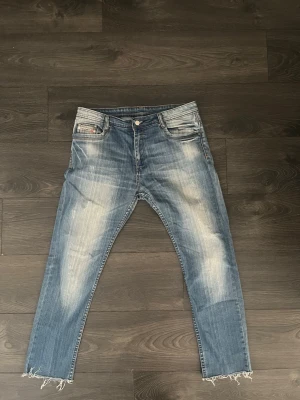 Vintage disel jeans - Säljer ett par blå jeans från Diesel med snyggt slitna detaljer och råa, fransiga benslut. . Perfekta för en avslappnad och trendig look. Hör gärna av dig vid funderingar😊