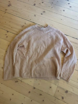 Stickad tröja från Acne i 100% ull, crewneck ljusrosa - Stickad crewnecktröja från Acne i 100% ull i ljusrosa. Tröjan har ribbstickade muddar vid ärmslut och nederkant. Perfekt inför höst och vinter!