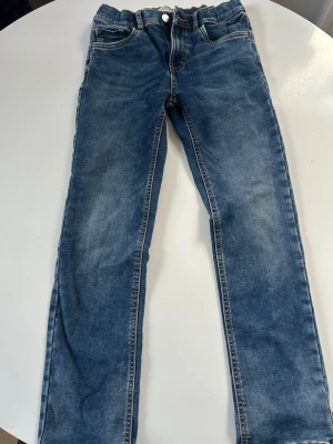 Blå raka jeans från Lindex - Snygga blå jeans från Lindex med raka ben och klassisk femficksmodell. Jeansen har en lätt tvättad look och kontrastsömmar. Perfekta för en avslappnad stil och passar till det mesta. Materialet är mjukt denim för skön känsla.