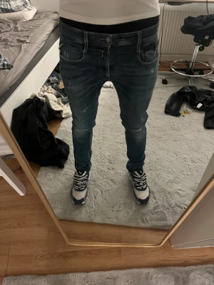 Replay Anbass jeans blå slim fit - Säljer ett par Replay Anbass jeans i blå tvätt med slim fit och snygga slitningar på benen. Klassisk femficksmodell med dragkedja och knapp framtill. Jeansen har en modern look och är gjorda i stretchigt denim för extra komfort. Nypris 1000kr. Krympt lite så sitter som 32.