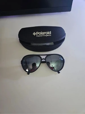 Svarta Polaroid pilotbågar solglasögon - Snygga svarta solglasögon från Polaroid med klassisk pilotform och spegelglas. Bågarna är tunna och stilrena, och glasen är polariserade för extra skydd mot solen. Perfekt accessoar för soliga dagar och ger en cool vibe. Priset går att diskuteras