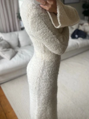 Krämvit stickad långklänning - Mysig krämvit långklänning i stickat material med figurnära passform och långa ärmar.🍁