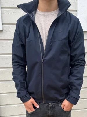 Ralph lauren performance jacket  - Snygg mörkblå vindjacka med hög krage och hel dragkedja framtill. Jackan har diskret logga på bröstet och raka ärmar med justerbara muddar. Tillverkad i ett lätt och vindtätt material som passar perfekt till blåsiga dagar.