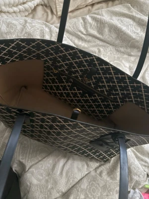 Svart väska  By Malene Birger - Snygg väska  från By Malene Birger i svart med vitt  grafiskt mönster. Väskan har långa handtag, rymligt innerfack och en innerficka med dragkedja. Materialet är tåligt konstläder och insidan är beige. Perfekt för dig som gillar stilrena accessoarer.