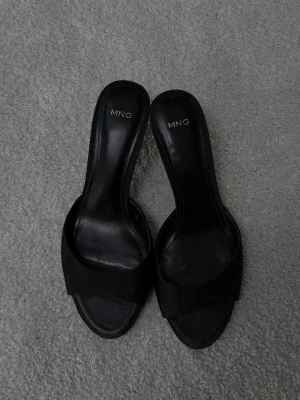 Kitten heel mango svart - Säljer dessa perfekta små svarta kitten heels från mango. De är i fint skick med en lagom klack, sköna att gå i. Är storlek 37 men passar även 36. Går inte att köpa längre. Remmen över foten är i ett tyg material. 