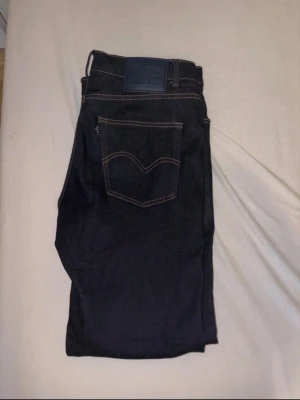 Levi's 511 mörkblå jeans W33 L32 - Säljer ett par mörkblå Levi's 511 jeans med klassisk femficksdesign och kontrastsömmar. Jeansen har en slim fit-modell och är tillverkade i slitstarkt denimtyg. Perfekta för dig som gillar en tidlös och clean look.