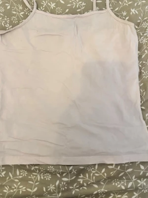 Rosa linnetopp med smala band - Säljer en enkel och stilren ljusrosa linnetopp med smala axelband. Toppen är ärmlös och har en rak passform, perfekt att matcha med olika outfits. Materialet känns mjukt och lätt mot huden.