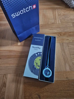 Swatch x Audemars Piguet Royal Pop - Cool klocka från Swatch x Audemars Piguet Royal Pop-kollektionen. Klockan har en ljusblå boett och matchande band, med en unik urtavla i blått och ljusblått. Kommer i originalförpackning och med Swatch-påse.