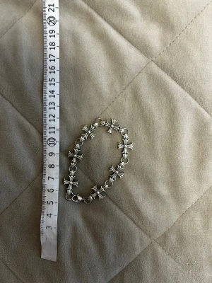 Chrome hearts Silverfärgat armband med korsdetaljer - Snyggt Chrome Hearts armband i silverfärg med flera korsformade länkar. Armbandet har en klassisk karbinhake och mäter cirka 17 cm långt. Perfekt accessoar för dig som gillar detaljer med lite edge.