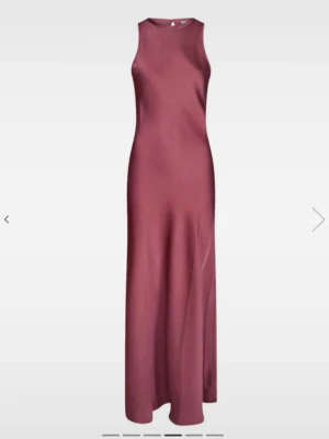 Balklänning  - Elegant långklänning i vinröd satin med ärmlös design och rund halsringning. Klänningen har en slät, figurnära passform och ett stilrent uttryck som passar perfekt till speciella tillfällen.