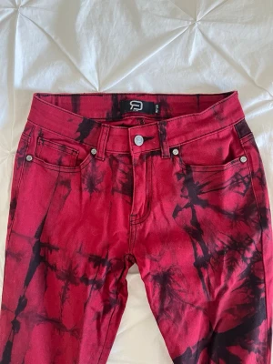 Röda bootcut jeans med batikmönster - Snygga röda jeans med svart batikmönster och bootcut passform. Har sytt dom till lågmidjade och de är gjort bra så de syns inte!!💕
