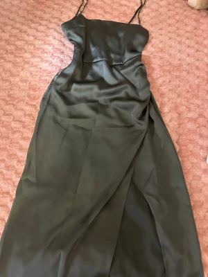 Svart långklänning från Zara - Elegant svart långklänning från Zara med tunna axelband och mjukt, glansigt material. Klänningen har en enkel och stilren design som ger en lyxig känsla. Perfekt för dig som gillar minimalistisk stil och vill ha något klassiskt i garderoben.