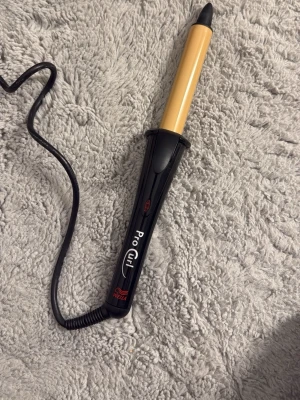 Pro Curl locktång svart/guld - Säljer en Pro Curl locktång i svart och guld med sladd. Tången har ett ergonomiskt handtag och en klämma för att hålla håret på plats när du lockar. Perfekt för att fixa snygga lockar snabbt och enkelt.