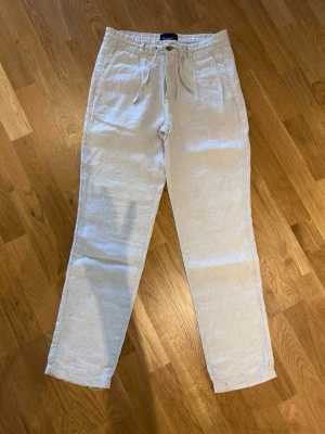 Beiga linnebyxor Bondelid - Bondelid linnebyxor i beige med raka ben och dragsko i midjan. Perfekta för en chill och stilren look. 
