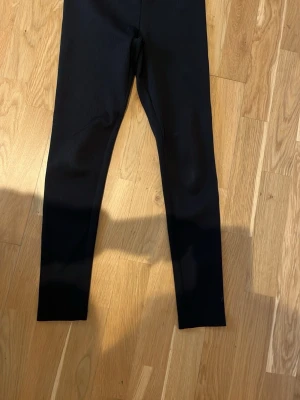 Svarta ribbade leggings - Säljer ett par svarta leggings med ribbad struktur. De har hög midja och smal passform som sitter tight längs benen. Perfekta att matcha med oversized tröjor eller hoodies. Materialet känns stretchigt och bekvämt.