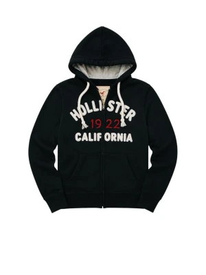 Svart Hollister hoodie med tryck - Svart hoodie från Hollister med dragkedja, vit broderad text 'Hollister California' och röda siffror '1922' på bröstet. Mjuk insida, vita grova dragsnören och huva med grått foder. Hör av dig vid fundering