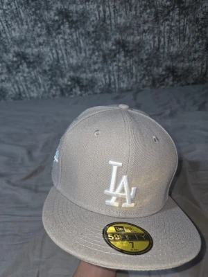 Beige LA keps från New Era - Snygg beige keps från New Era med LA Dodgers-logga broderad framtill i vitt och en specialpatch på sidan. Klassisk 59FIFTY-modell med rak skärm och strukturerad passform. Perfekt för dig som vill ha en clean och stilren look.