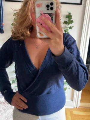 Mörkblå omlottopp från G-Star RAW - Snygg mörkblå omlottopp från G-Star RAW med djup V-ringning och bred mudd i midjan. Tröjan har långa ärmar och är gjord i mjukt sweatshirtmaterial. Perfekt för en chill och trendig look.