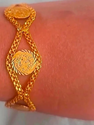 Guldarmband med myntdetaljer - Snyggt armband i guldfärgad metall med tre runda myntliknande dekorationer. Kedjan är tvinnad och ger en unik look, perfekt för dig som gillar statement-smycken. Passar till många olika stilar och är lätt att matcha med andra accessoarer.