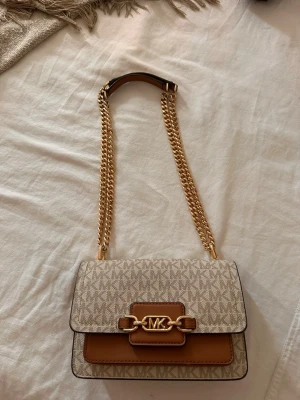Beige axelväska Michael Kors - En superfin väska från MK som tyvärr ej kommer till användning längre. Inuti är den lite missfärgad pga smink och annat som kommit o kontakt med väskan. Inget som syns på utsidan dock. Köpt för ca 2800