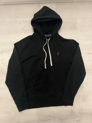 Ralph lauren hoodie svart - Säljer en klassisk svart hoodie från Ralph Lauren. Stilren och tidlös modell som passar till allt och aldrig går ur stil.  • Storlek: M • Färg: Svart • Skick: Mycket fint skick • Mjuk och bekväm passform • Perfekt för vardag, skola och fritid • Enkel att matcha med både jeans, chinos och mjukisbyxor • Klassisk Ralph Lauren-design med broderad logga