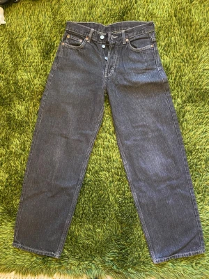Weekday mörkgrå Sphere Low Loose jeans - Säljer ett par mörkgrå Sphere Low Loose jeans med raka ben. Klassisk femficksmodell med knappgylf och kontrastsömmar. Något små på mig som är 174cm.