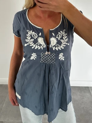 Odd Molly Blå broderad blus  - Säljer en otroligt fin blå blus från Odd Molly i nyskick. Toppen har vita broderier och en rosett framtill. Använd vid ett fåtal tillfällen och inga defekter. Strl 1 vilket jag skulle säga motsvarar S.