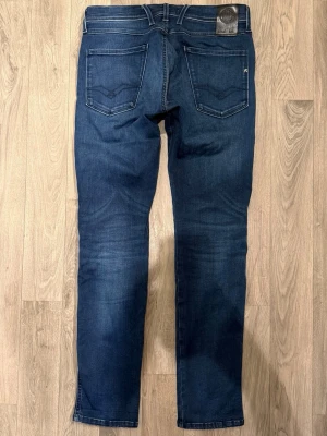 Replay Anbass Hyperflex Jeans Mörkblå W31/L32 - Slim Fit - Replay Anbass mörkblå jeans i Hyperflex stretchdenim som ger en väldigt bekväm och flexibel passform, slim fit modell som sitter snyggt och funkar till allt, storlek W31/L32, midja 40 cm, ytterbenslängd 101 cm, benöppning 15,5 cm, modellen är 185cm & väger 65kg, i fint skick.
