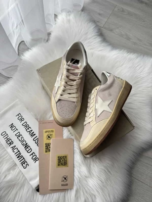 Beige sneakers från Golden Goose - Stilrena sneakers från Golden Goose i beige canvas och mocka med vit stjärndetalj på sidan. Skorna har vita skosnören, perforerad tå och en retroinspirerad sula i beige och brunt. Perfekta för dig som gillar en avslappnad men trendig look.