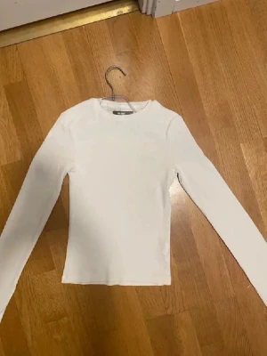 Vit långärmad topp från bikbok  - En enkel och stilren vit långärmad topp från bikbok. M. Modellen är figurnära med rund halsringning och tillverkad i mjuk bomull. Perfekt att matcha med jeans eller kjol för en clean look.