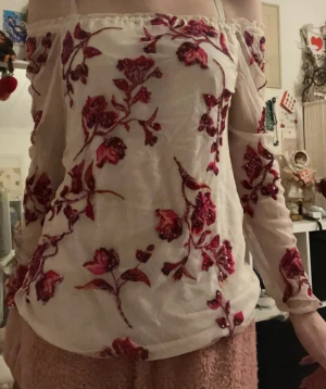 Offshoulder blommig topp - En jätte fin unik offshoulder topp i vit mesh på armarna  med broderade blommor i rött och rosa samt paljettdetaljer. Xs men passar s oxå, jag är s i bilden