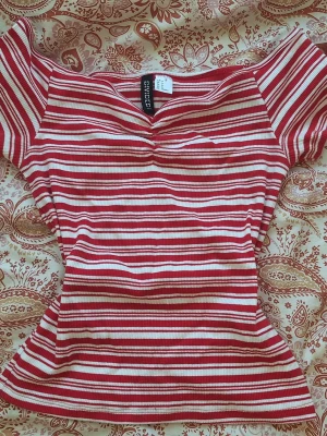 ranging kortärmad topp från H&M - säljer en röd och vit randig topp från H&M. toppen är ribbad och har korta ärmar samt en snygg rynkdetalj vid bysten. passar bra till sommaren