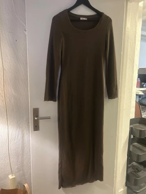 Brun lång stickad klänning Nelly - Långärmad brun stickad klänning från Nelly i storlek XS. Klänningen har rund halsringning och är figurnära med en enkel, stilren design. 